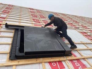 Monteur met bouwhelm plaatst een HydroTop in een schuin dak in aanbouw